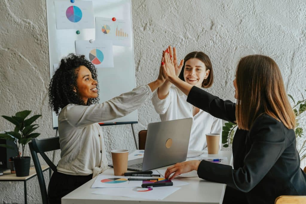 3 sales reps in a team meeting giving a high five