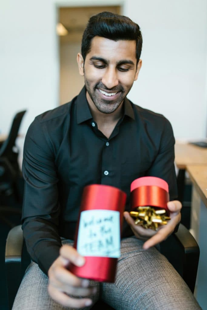 A person in office wear opens a present with text saying welcome to the team. Effective onboarding helps to get your new hires up to speed.
